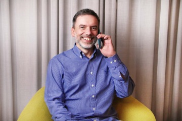 Imageová fotka muže v bílé košili hledícího do dálky sedícího ve člunu na moři s horizontem v pozadí